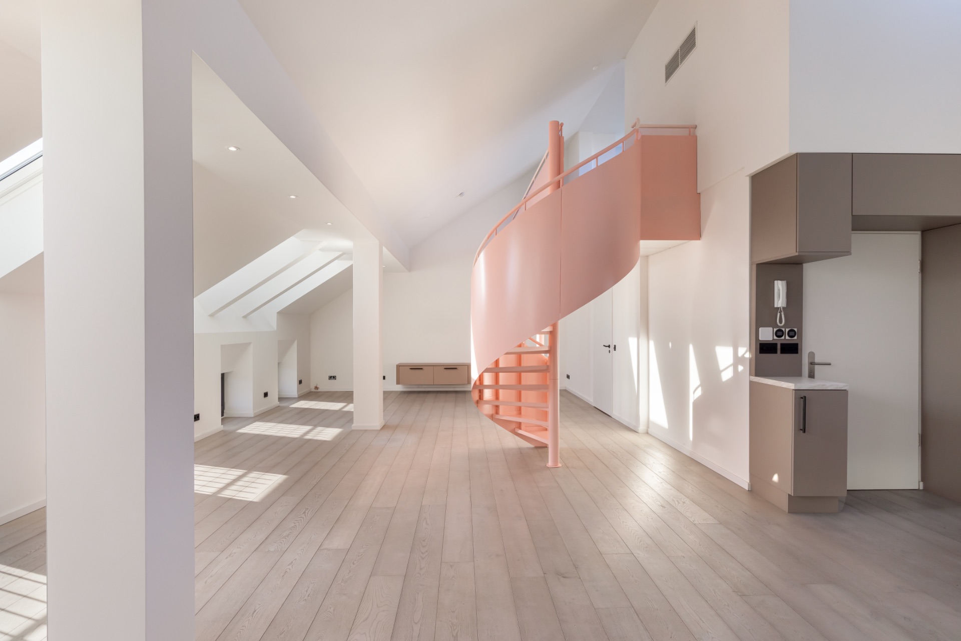 Helles Wohnzimmer mit rosa Wendeltreppe und großer Fensterfront.