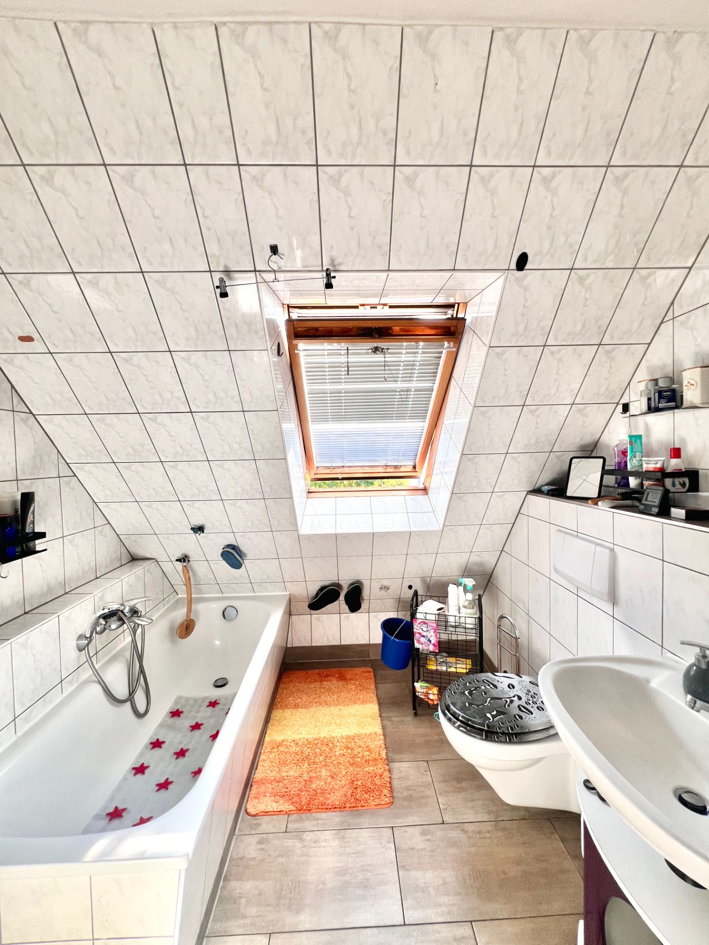 Helles Badezimmer mit Badewanne, Waschbecken, Toilette und Dachfenster.