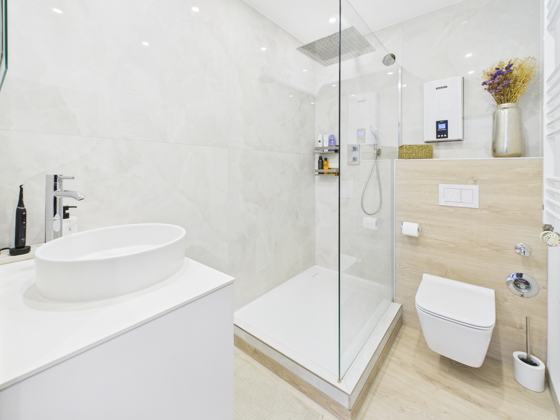 Modernes Bad mit bodengleicher Dusche, Waschbecken und wandhängender Toilette.