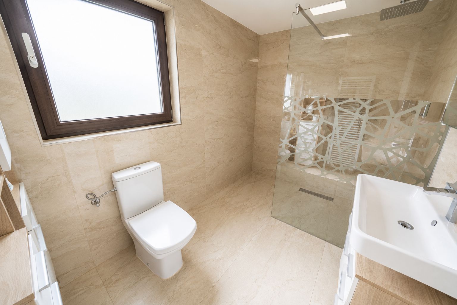Modernes Badezimmer mit Toilette, Fenster, Waschbecken und begehbarer Dusche mit Glaswand.