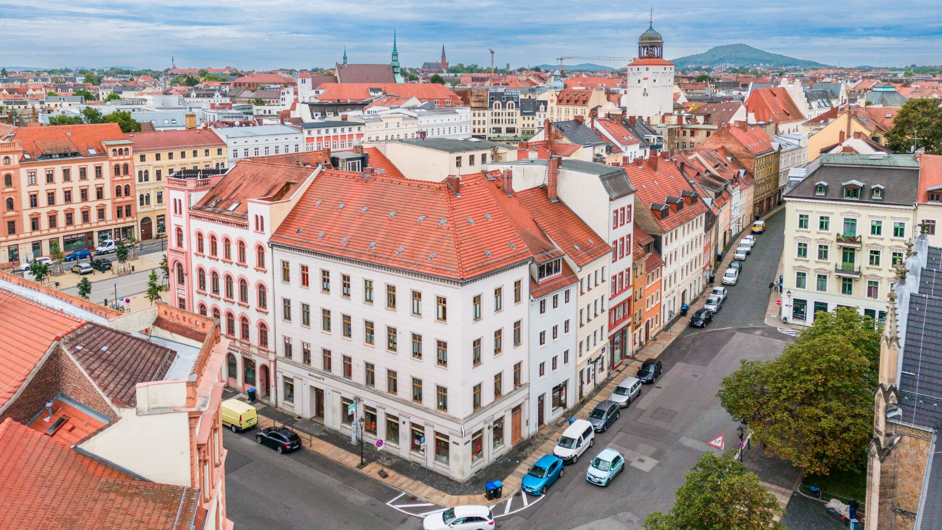 Luftaufnahme von Wohnhäusern mit roten Dächern an einer Straßenecke in einer Stadt.