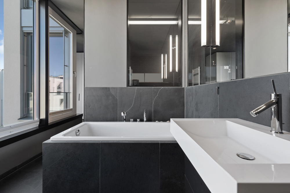 Modernes Badezimmer mit großer Badewanne, Waschbecken und offenem Fenster.