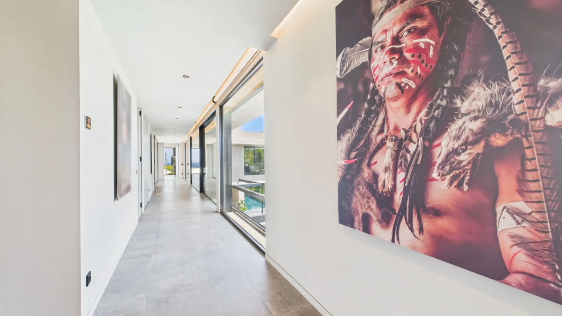 Heller Flur mit großen Fenstern und einem Porträt an der Wand.