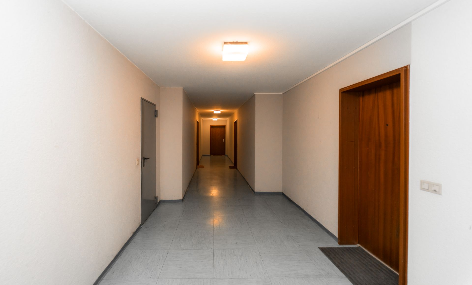 Heller Flur mit mehreren Wohnungstüren in einem Wohngebäude.