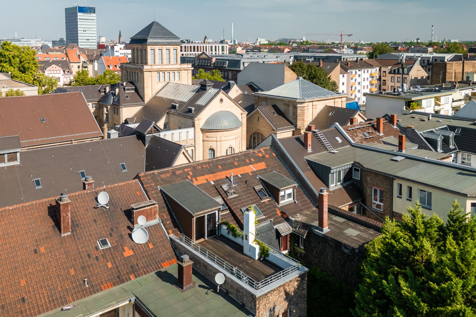 Blick auf mehrere Wohnhäuser mit Ziegeldächern und Satellitenschüsseln in einer Stadt.