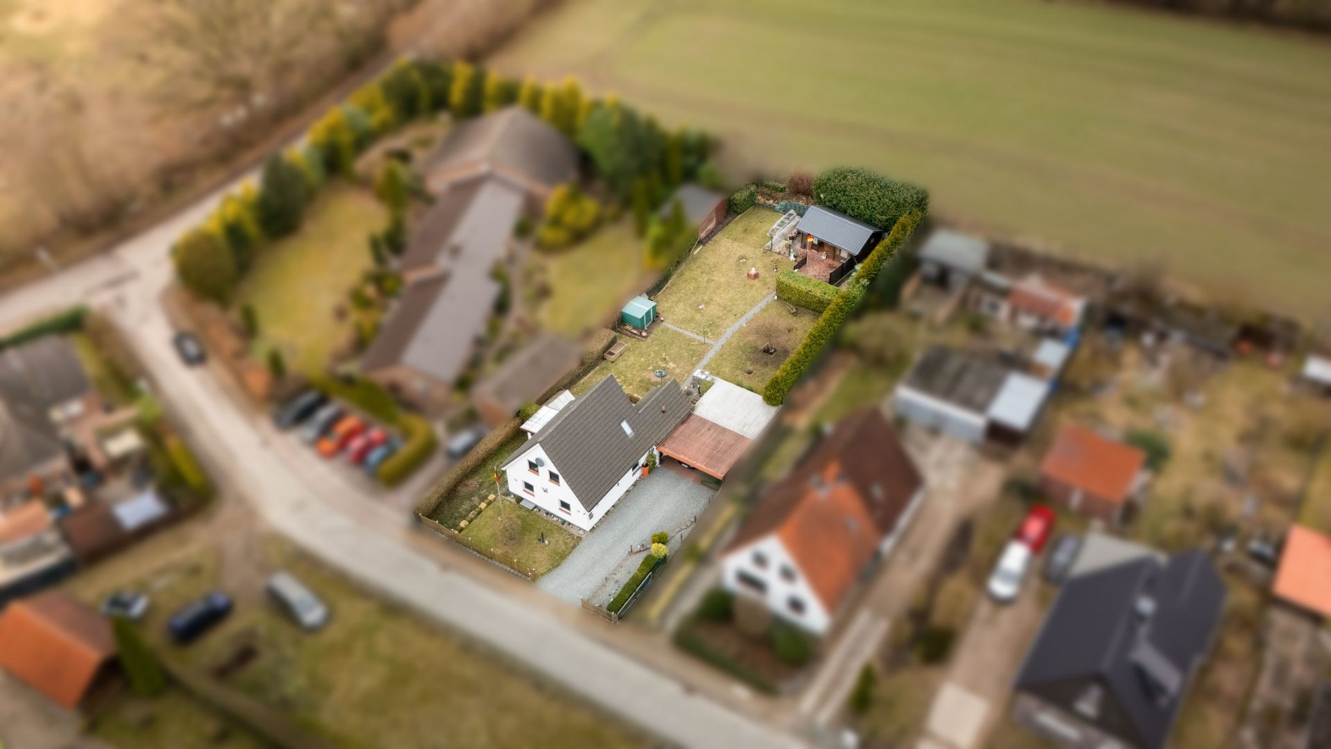 Luftaufnahme eines Einfamilienhauses mit großem Garten und umliegenden Nachbarhäusern.