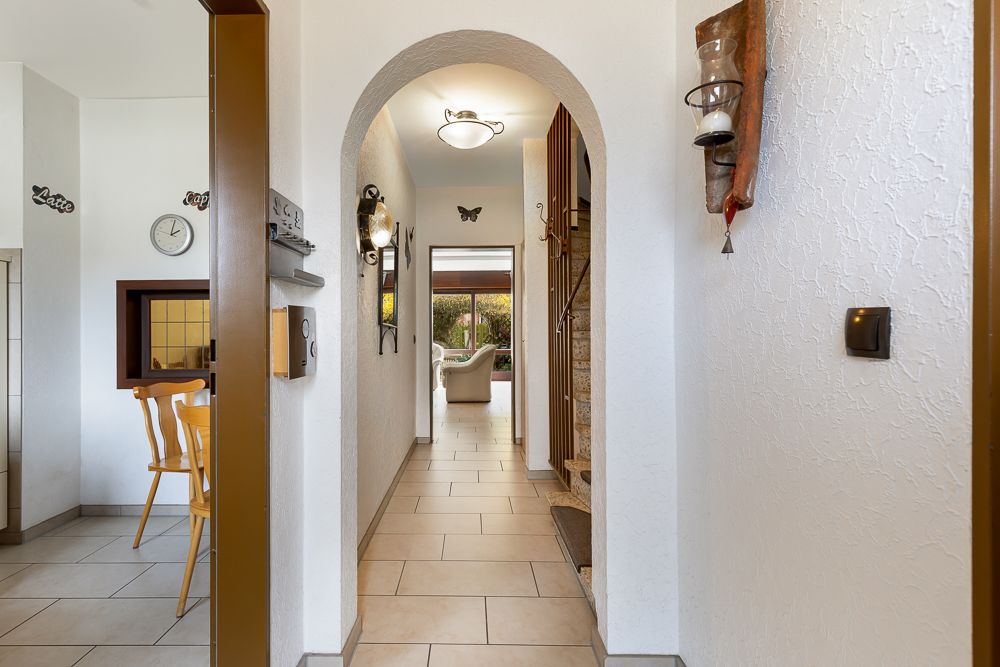 Heller Flur mit Rundbogen, Sicht auf Esszimmer und Wohnzimmer mit Sofa im Hintergrund.