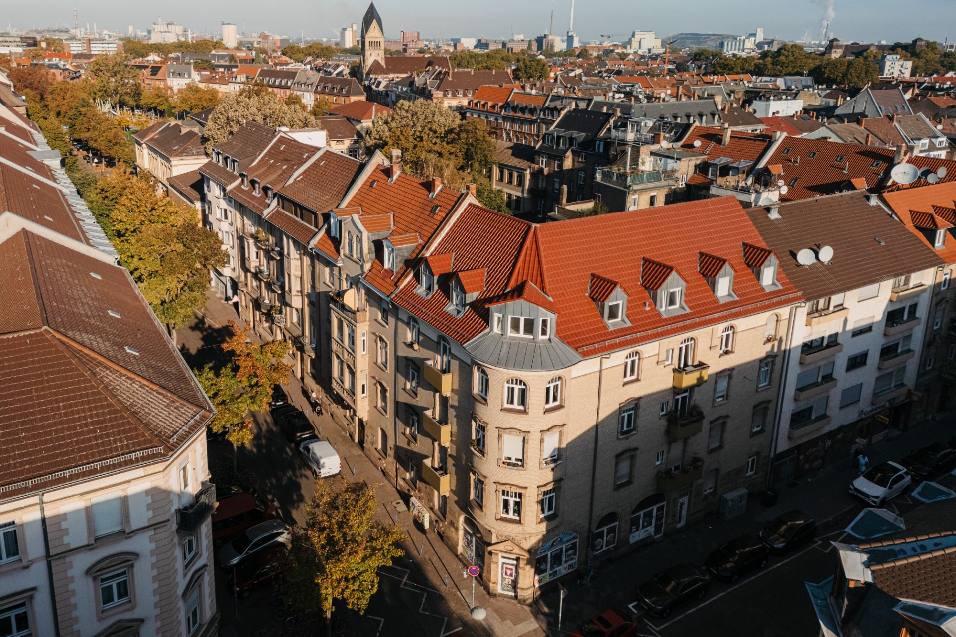 Luftaufnahme von Wohngebäuden mit roten Dächern und Bäumen entlang einer Straße.
