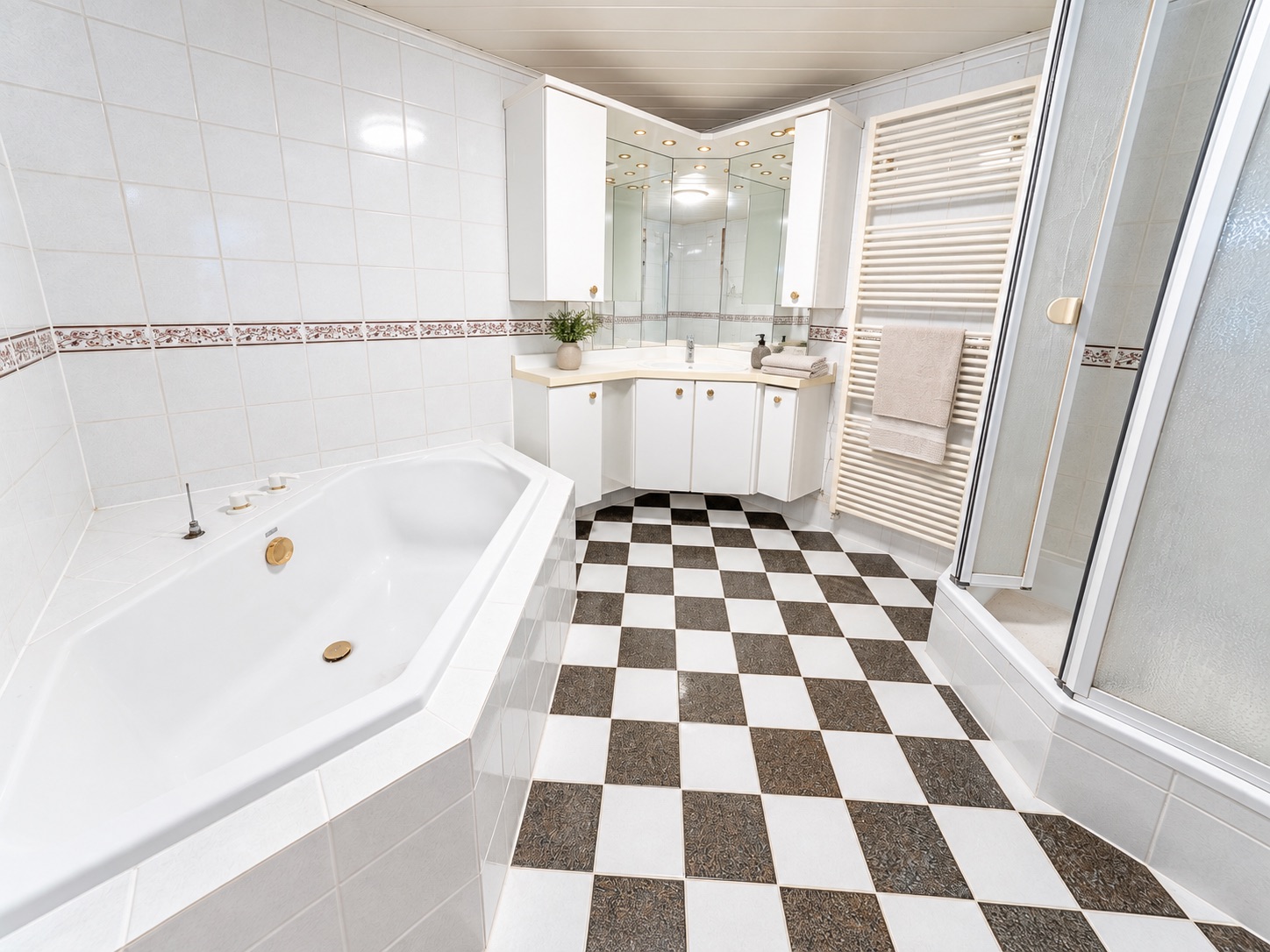 Modernes Badezimmer mit Eckbadewanne, Dusche, Spiegelschrank und schwarz-weiß kariertem Boden.