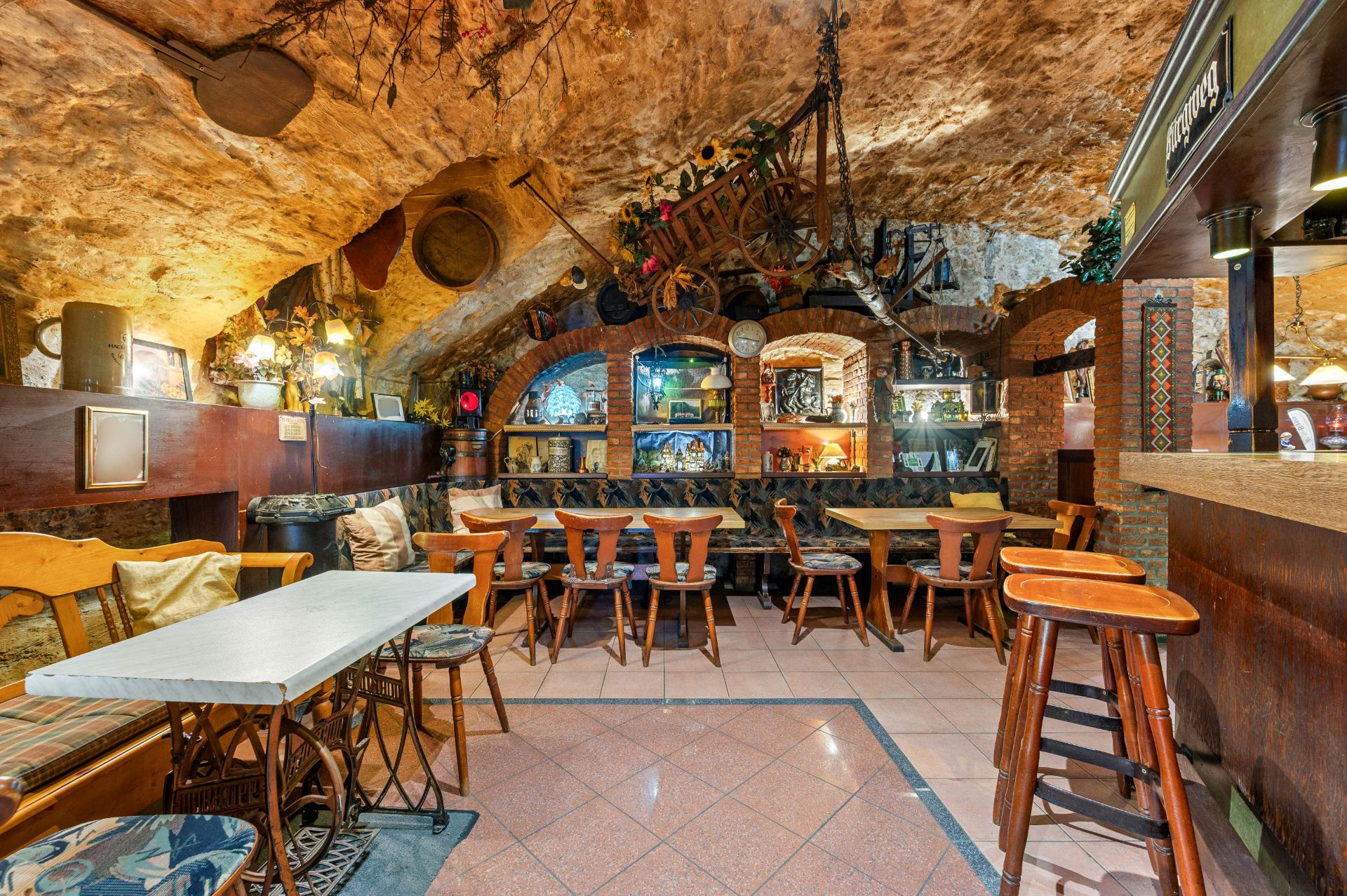Gemütlicher Raum mit holzgeschnitzten Stühlen, rustikalem Gewölbe und Dekorationen an der Wand.