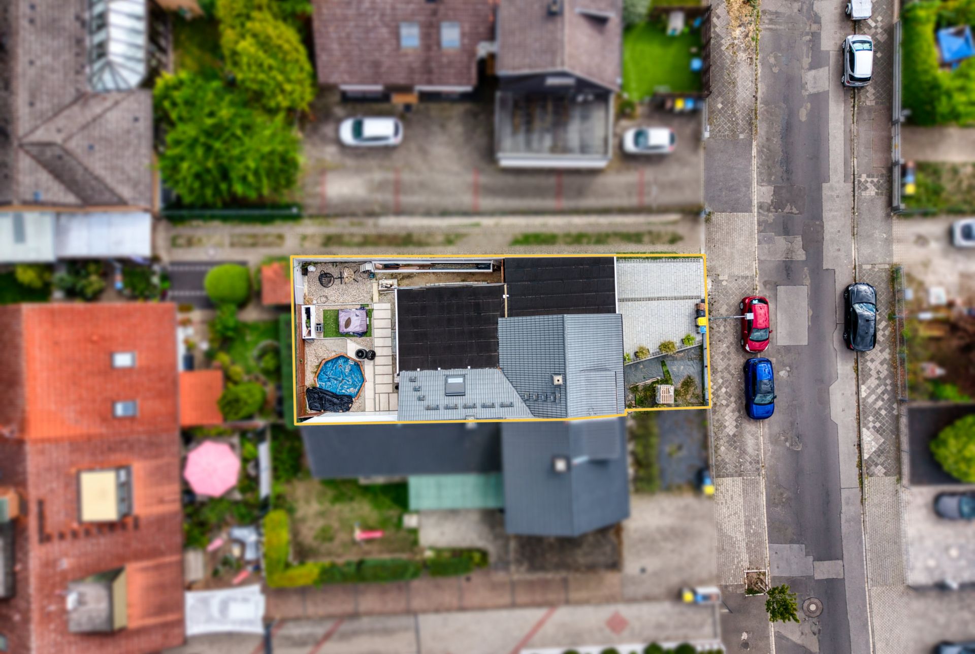 Luftaufnahme eines rechteckigen Wohnhauses mit Innenhof und angrenzender Straße.