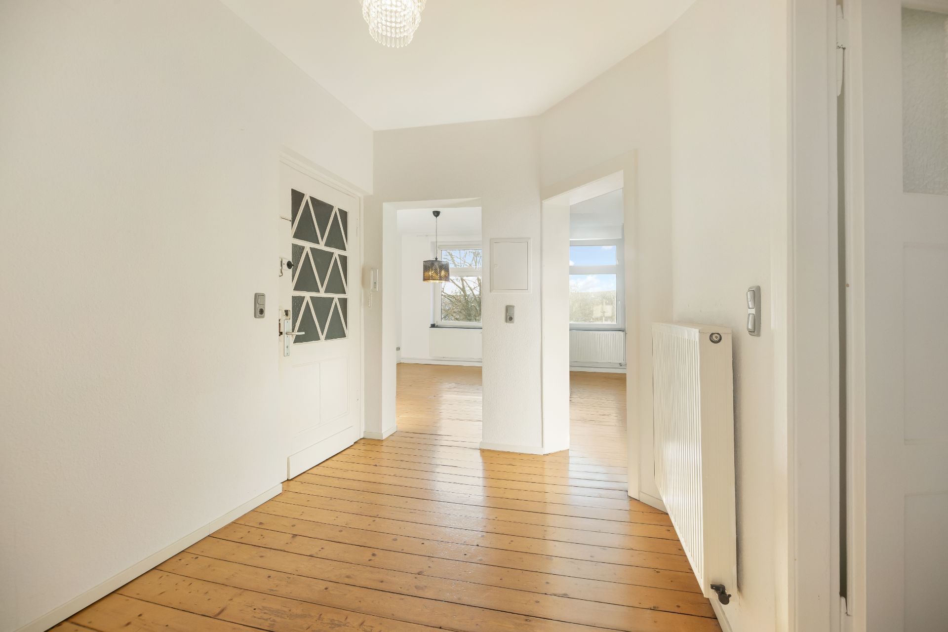 Heller Flur mit Holzboden, weißen Wänden und Blick in zwei weitere Zimmer.