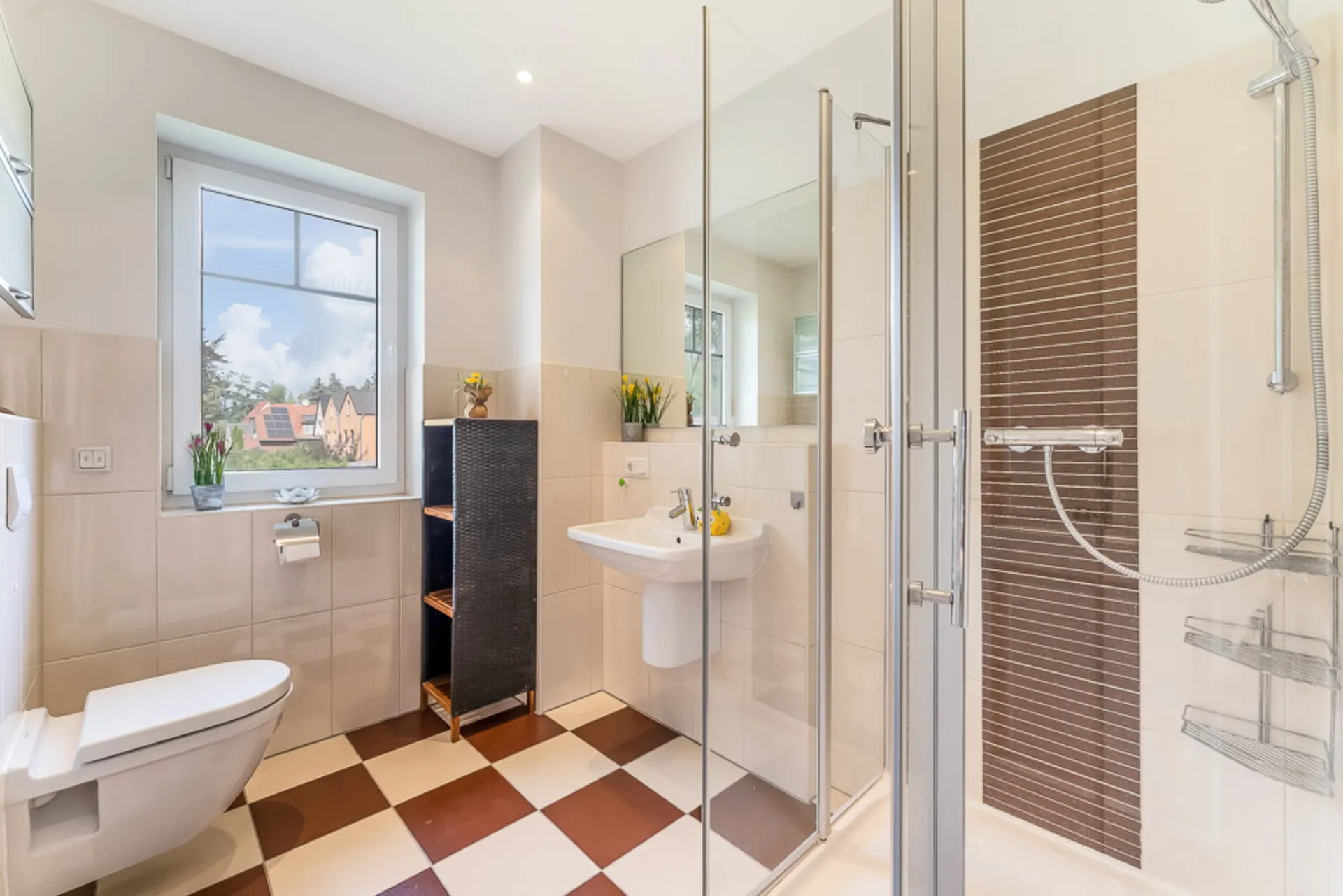 Modernes Badezimmer mit Dusche, Waschbecken, WC und kariertem Fliesenboden.