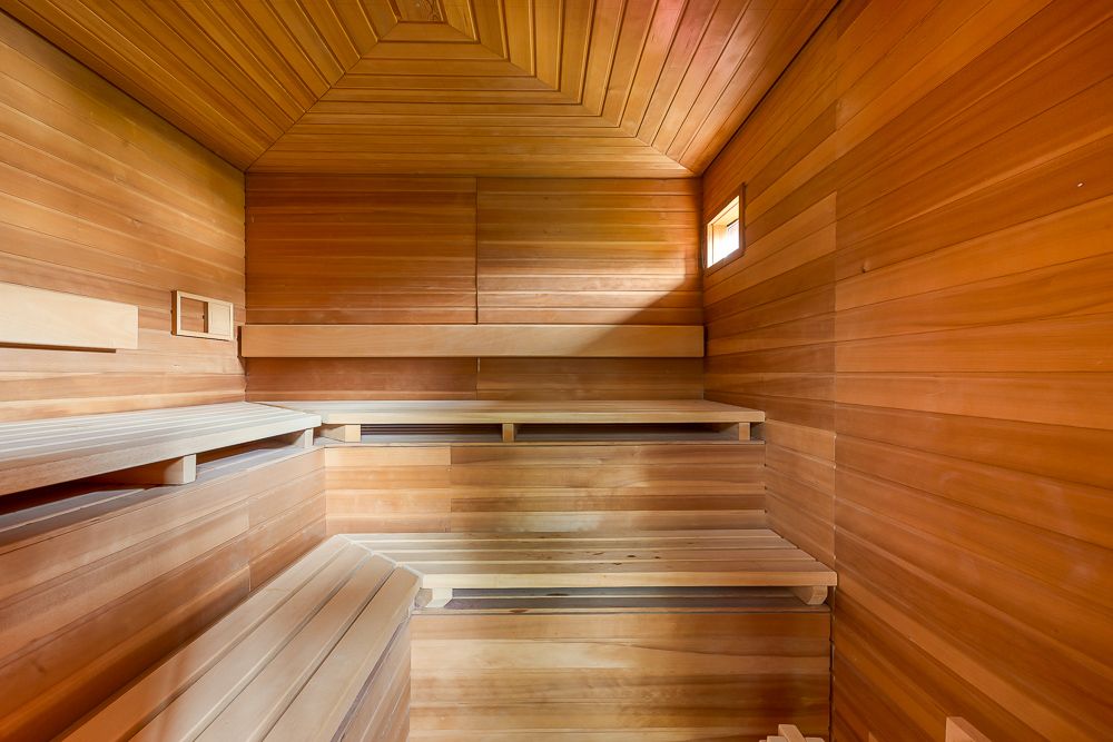 Holzverkleidete Sauna mit mehreren Sitzbänken und kleinem Fenster.