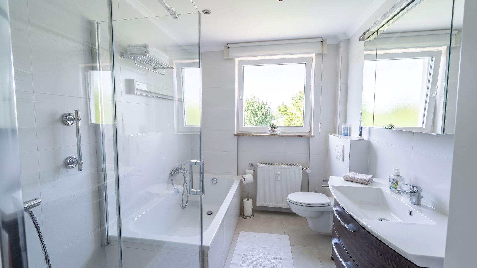 Modernes Badezimmer mit Badewanne, Dusche, WC und zwei Fenstern.