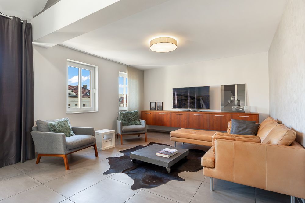 Modernes Wohnzimmer mit Ledersofa, zwei Sesseln, Couchtisch und großem Fernsehschrank.