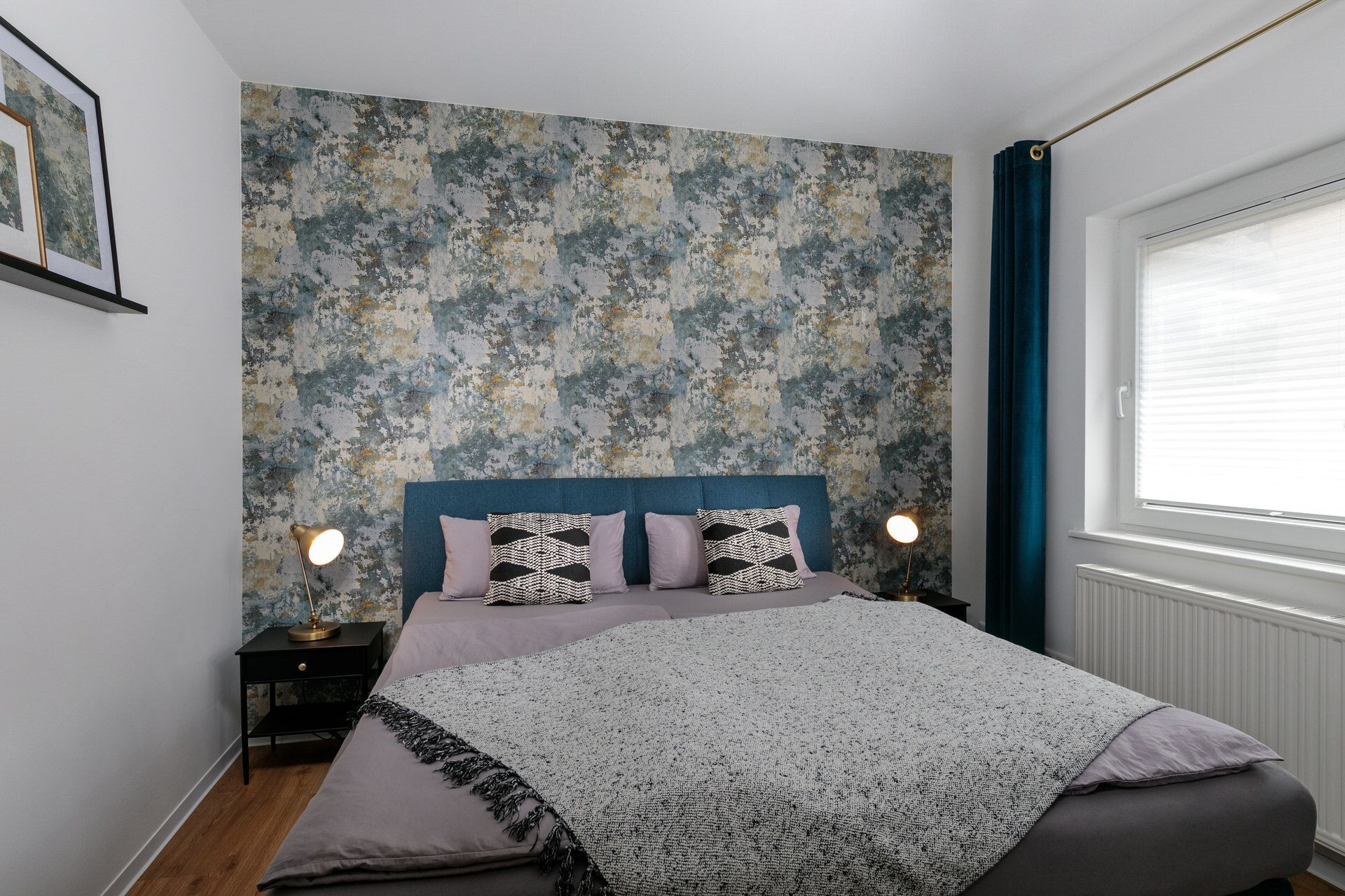 Schlafzimmer mit Doppelbett, gemusterter Tapete und zwei Nachttischen mit Lampen.