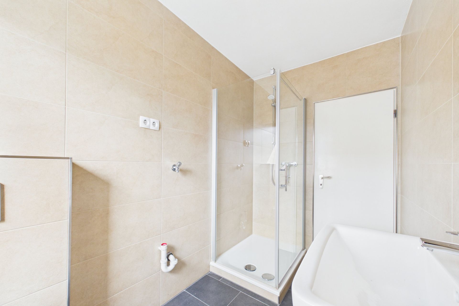 Modernes Bad mit Dusche, Badewanne und heller Fliesenwand.