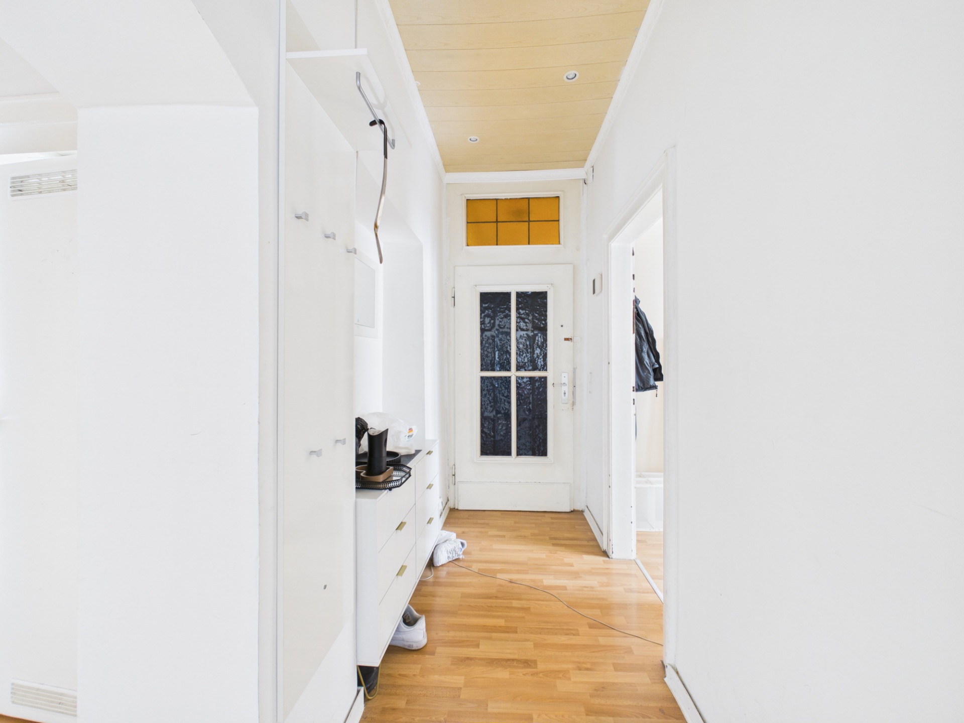 Heller Flur mit Holzboden, weißen Wänden und einer Glastür am Ende.