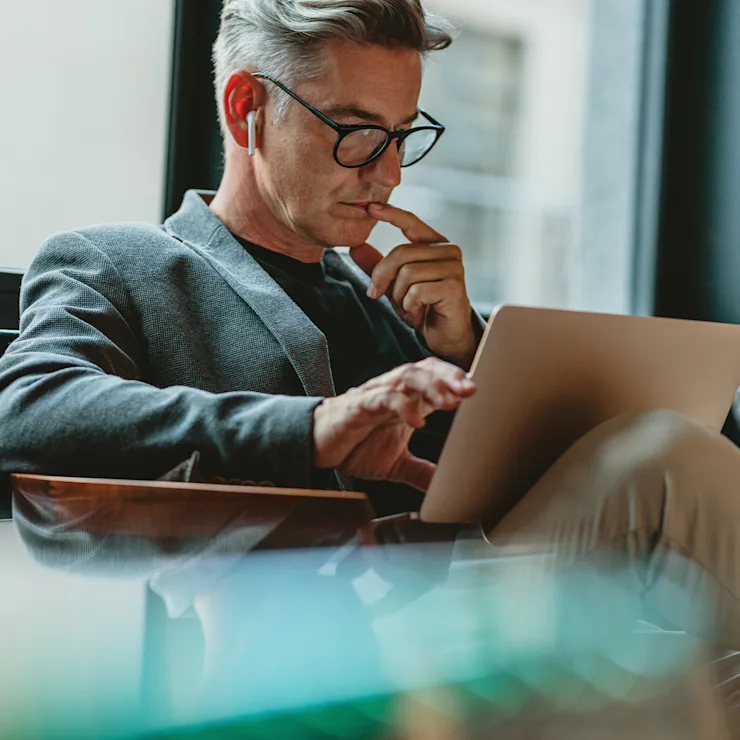 Ein Mann mit Brille sitzt am Fenster und arbeitet an einem Laptop.