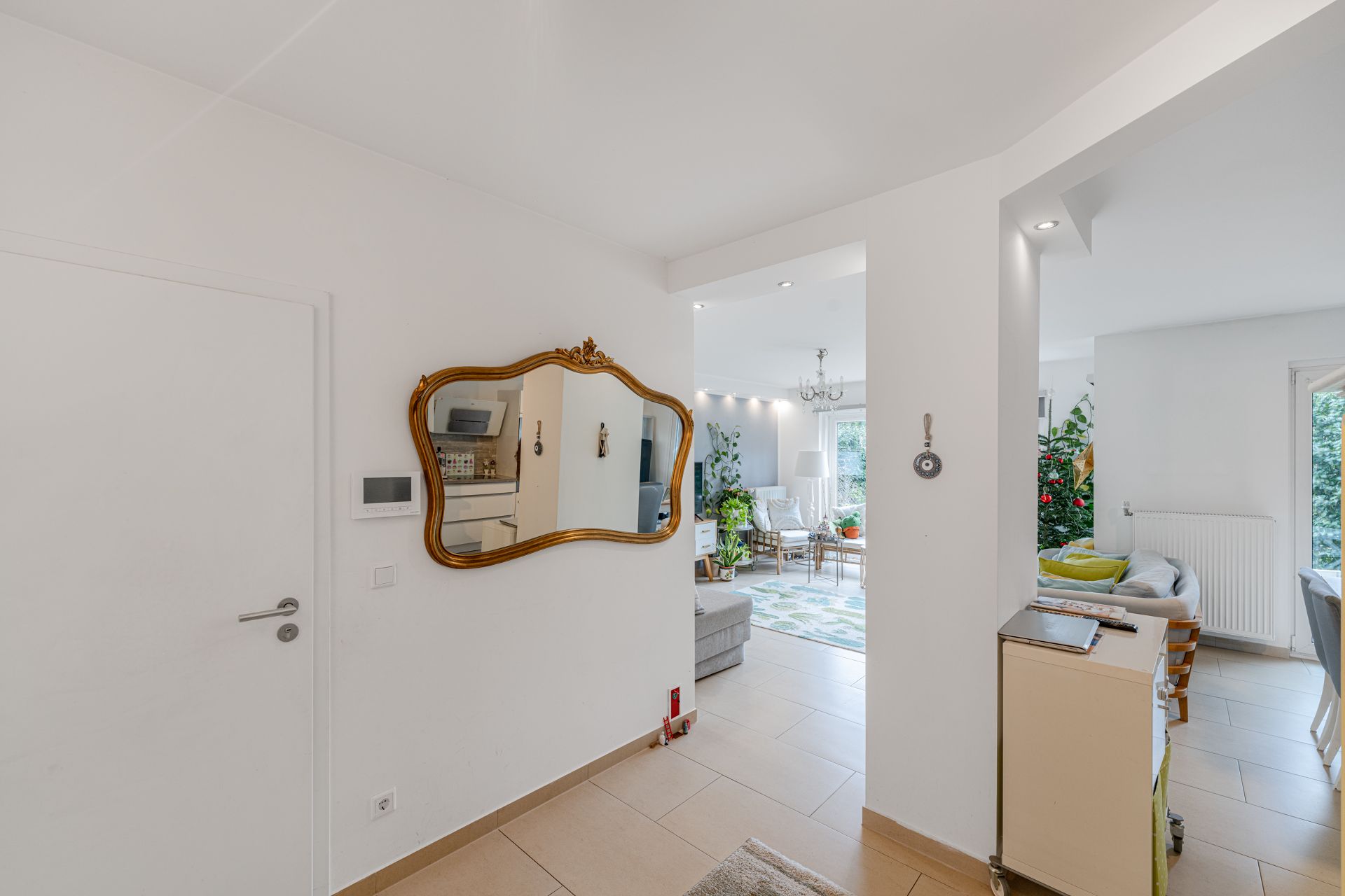 Heller Flur mit Spiegel, Blick ins Wohnzimmer mit Sofa und viel Tageslicht.