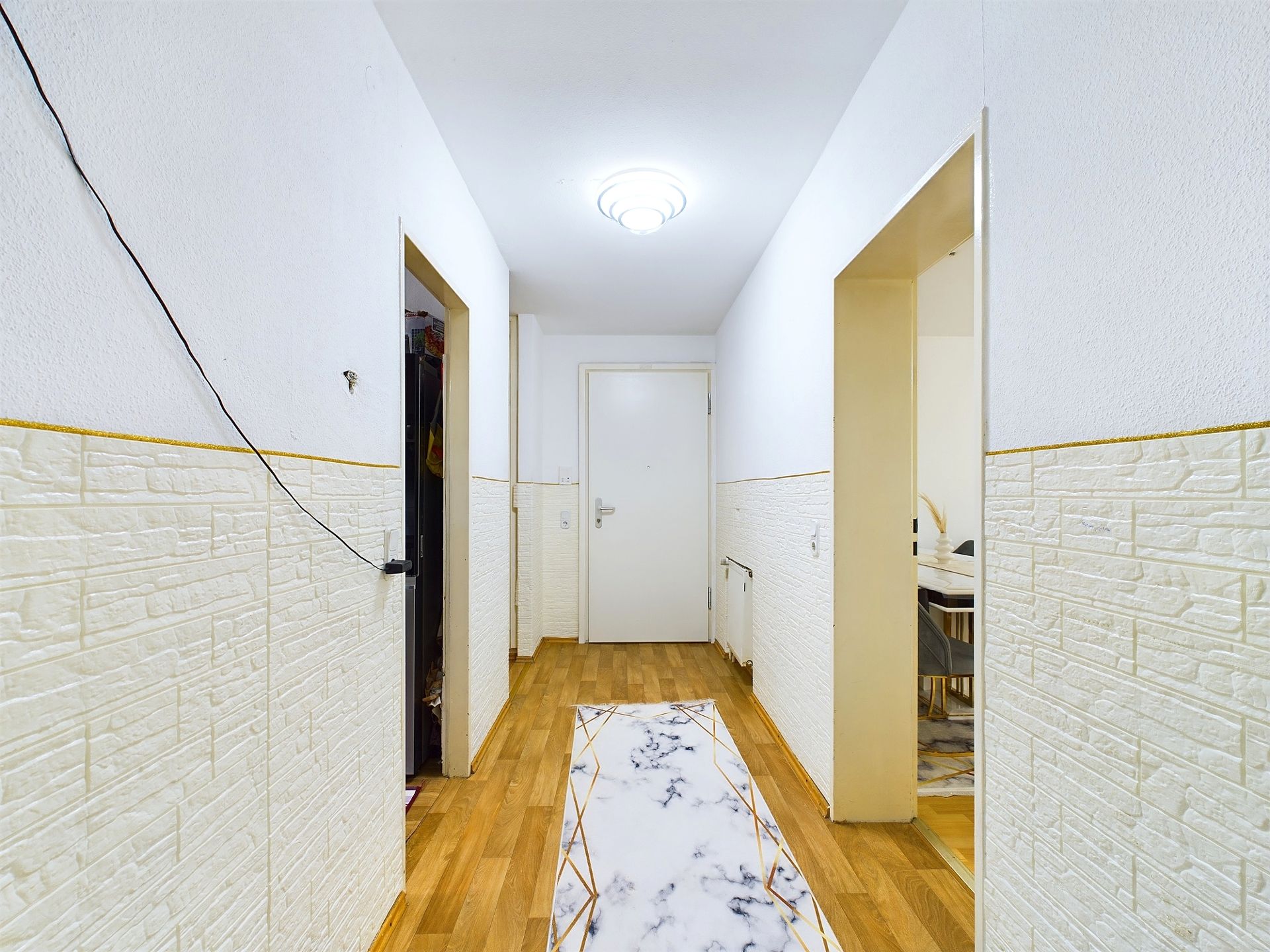 Heller Flur mit Holzboden, Teppichläufer und weißen Wänden in einer Wohnung.