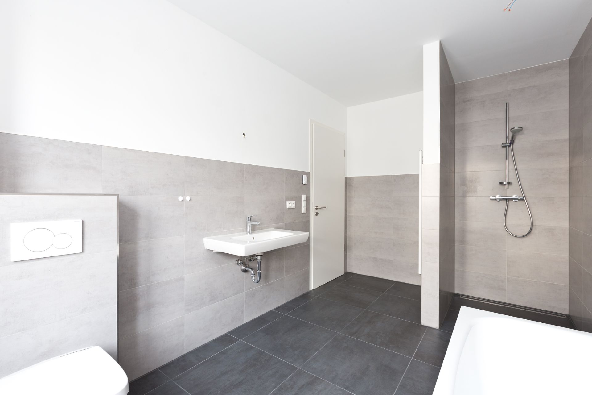 Helles Badezimmer mit Toilette, Waschbecken, offener Dusche und Badewanne.