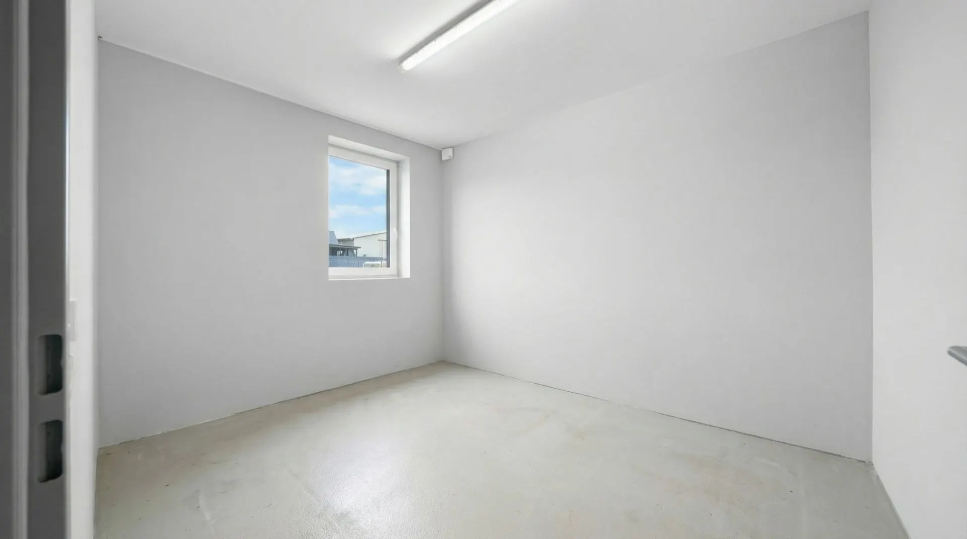 Leeres Zimmer mit weiß gestrichenen Wänden, Fenster und Deckenleuchte.