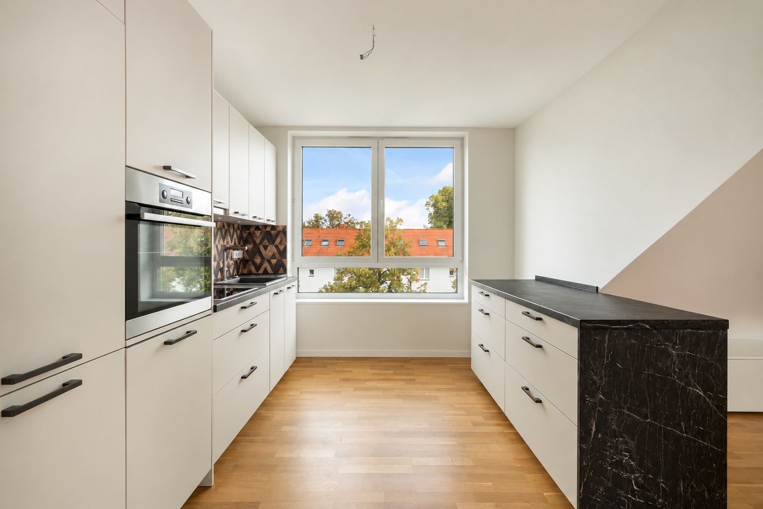 Moderne Küche mit weißen Schränken, Holzboden und großem Fenster.