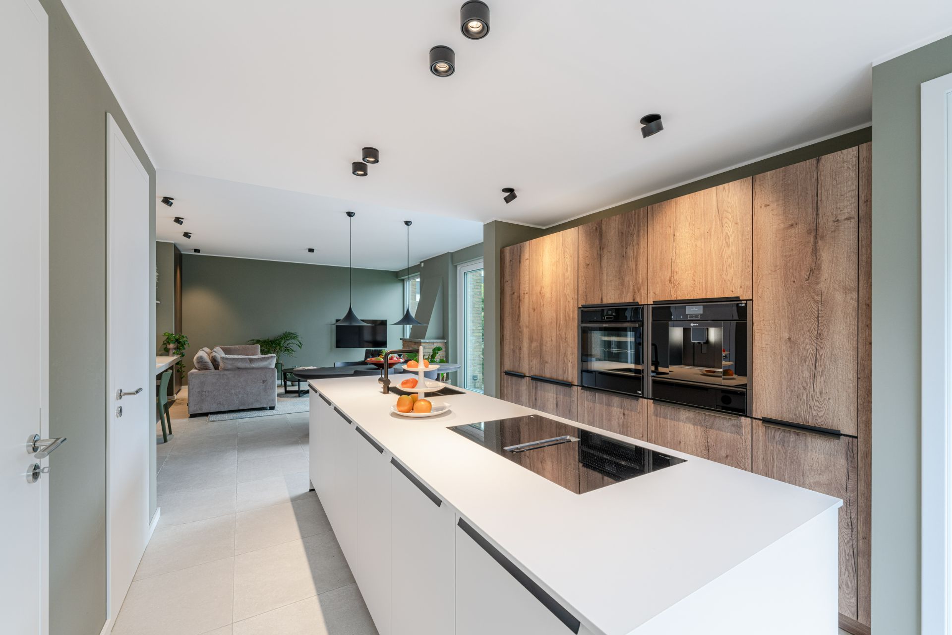 Moderne Küche mit Kochinsel, Holzfronten und Blick auf Wohnzimmer mit Sofa.