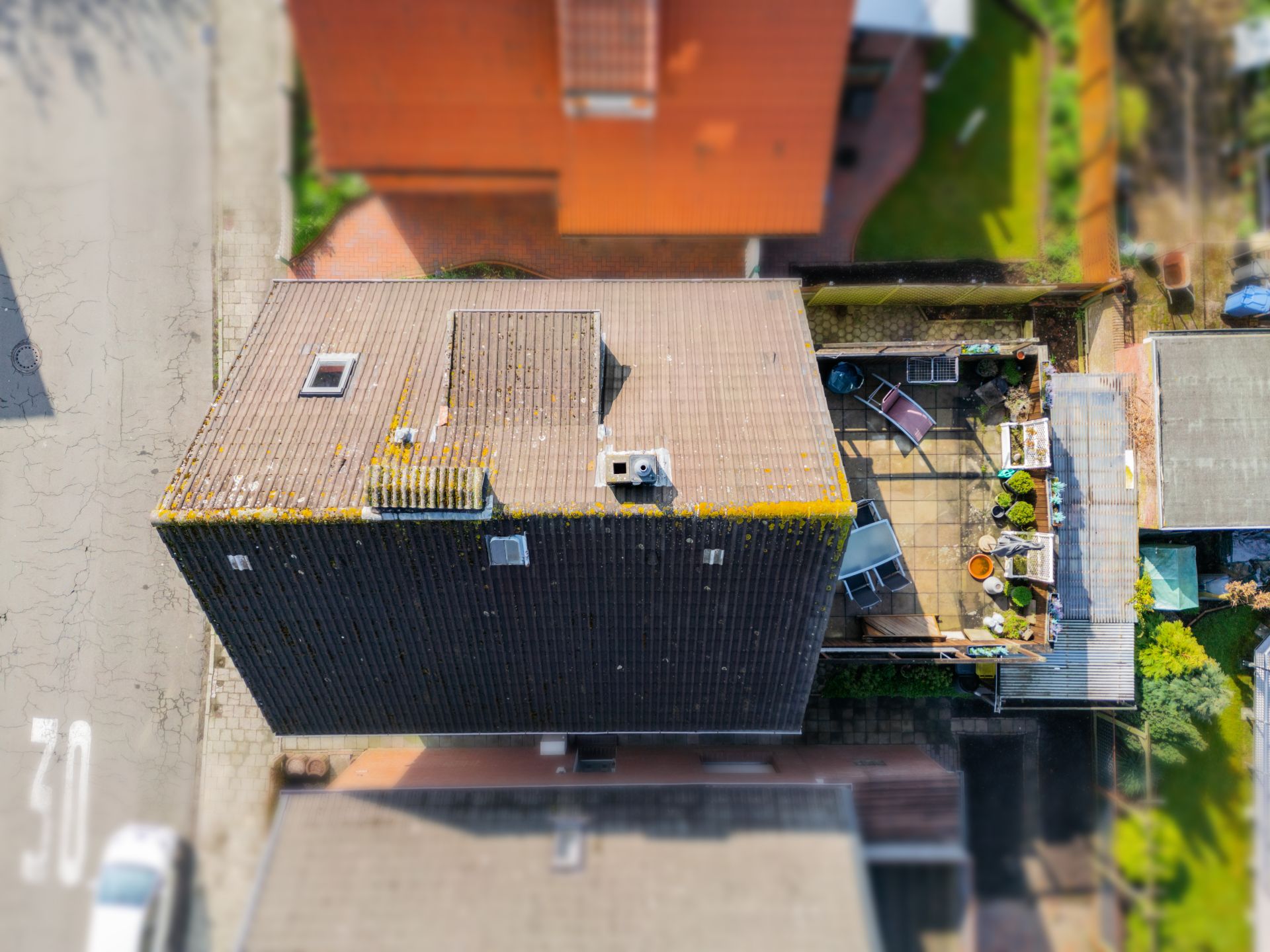 Luftaufnahme eines Hauses mit Dachterrasse und mehreren Pflanzen auf der Terrasse.