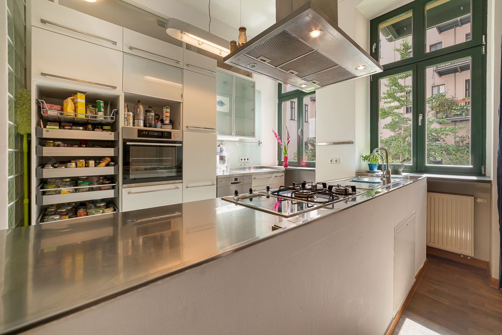 Moderne Küche mit Edelstahltresen, Gaskochfeld, großem Fenster und offenem Vorratsschrank.