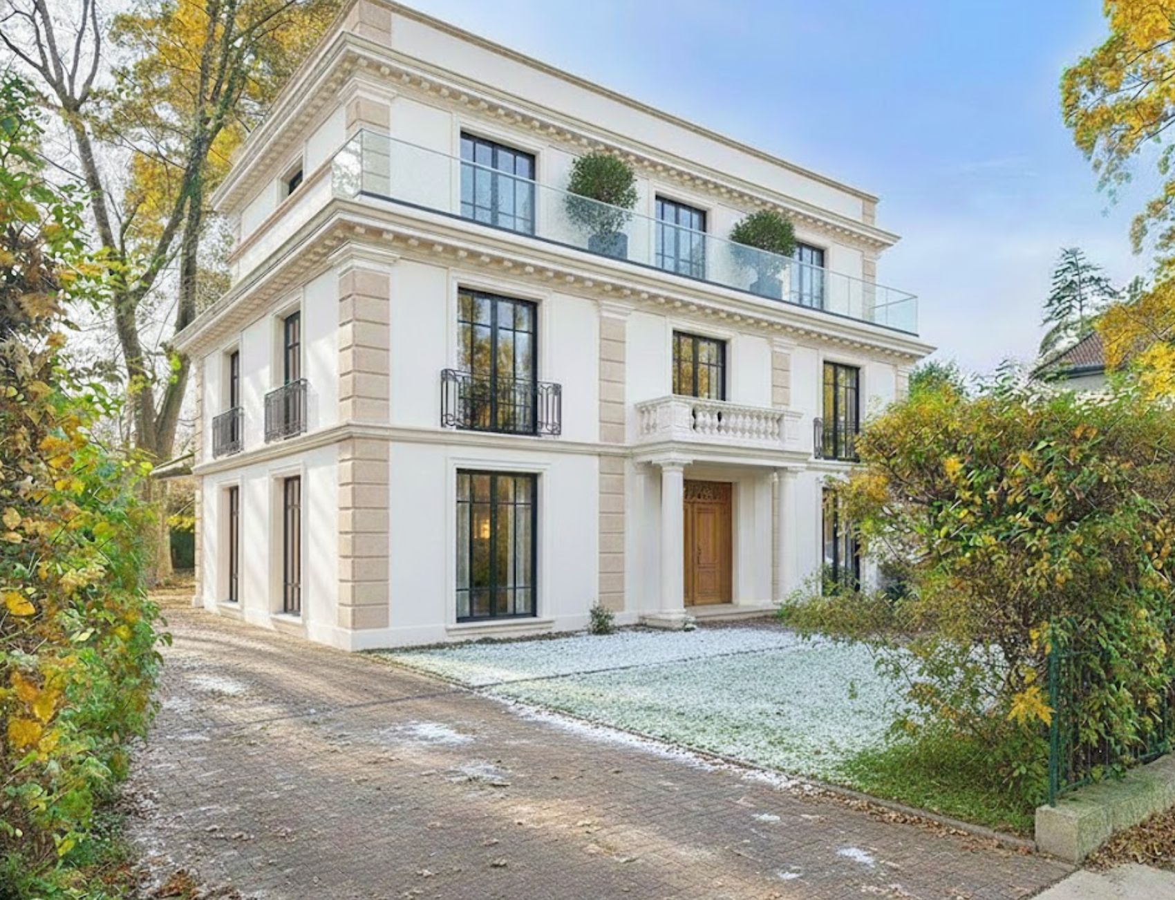 Modernes, dreistöckiges Wohnhaus mit großen Fenstern und Balkon, umgeben von Bäumen und Einfahrt.