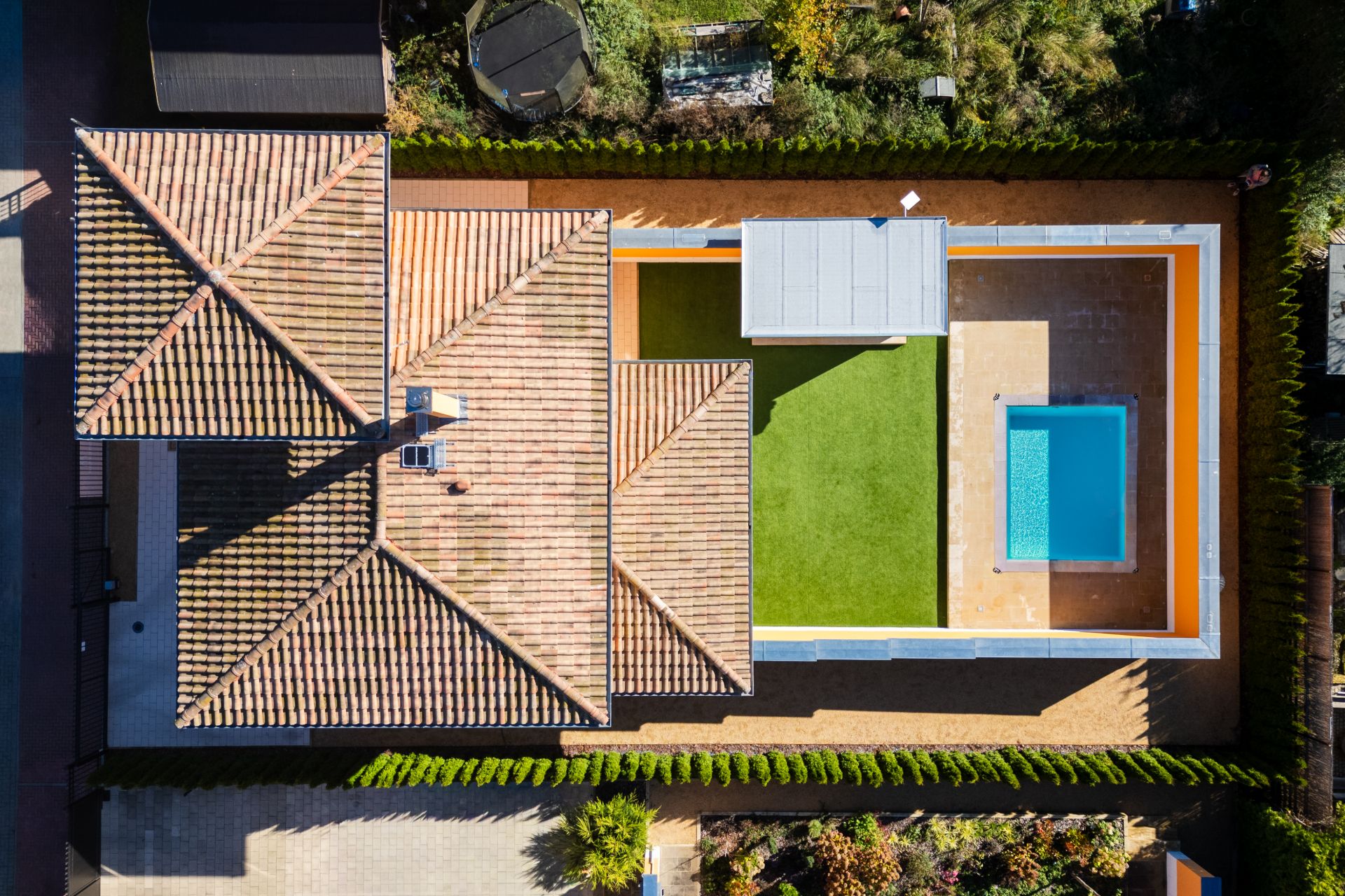 Luftaufnahme eines Hauses mit Ziegeldach, Garten und rechteckigem Pool im Innenhof.
