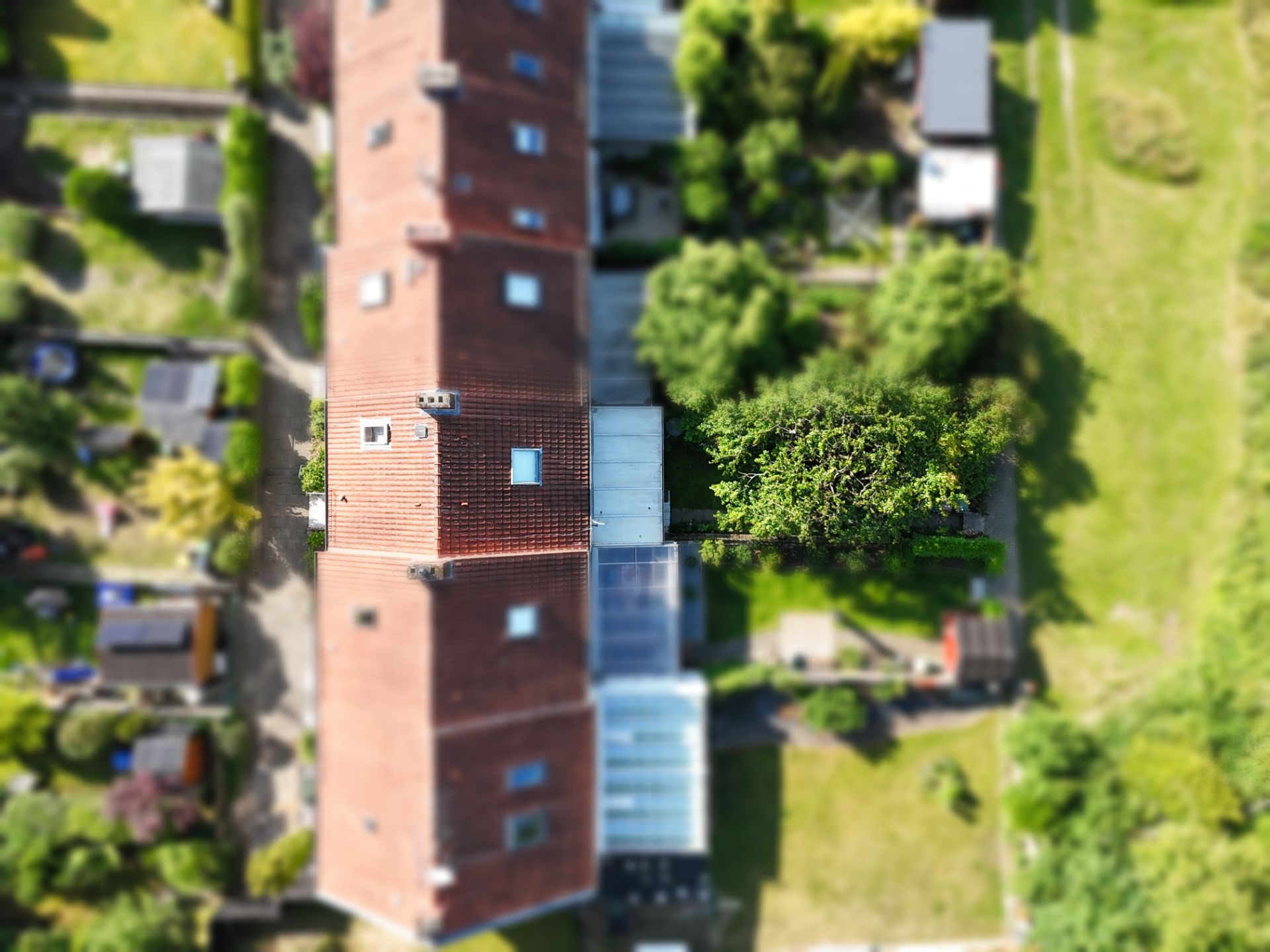 Luftaufnahme eines Reihenhauses mit Gärten und Bäumen im Hinterhof.
