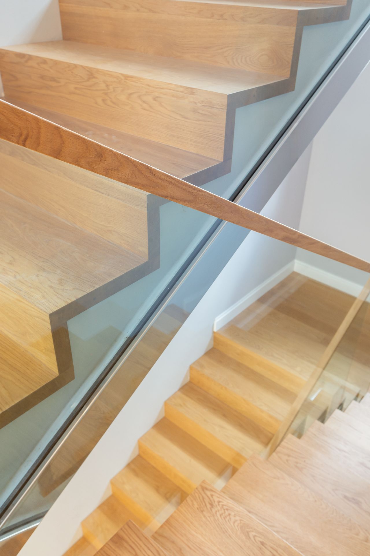 Moderne Holztreppe mit Glasgeländer in einem Wohnhaus.