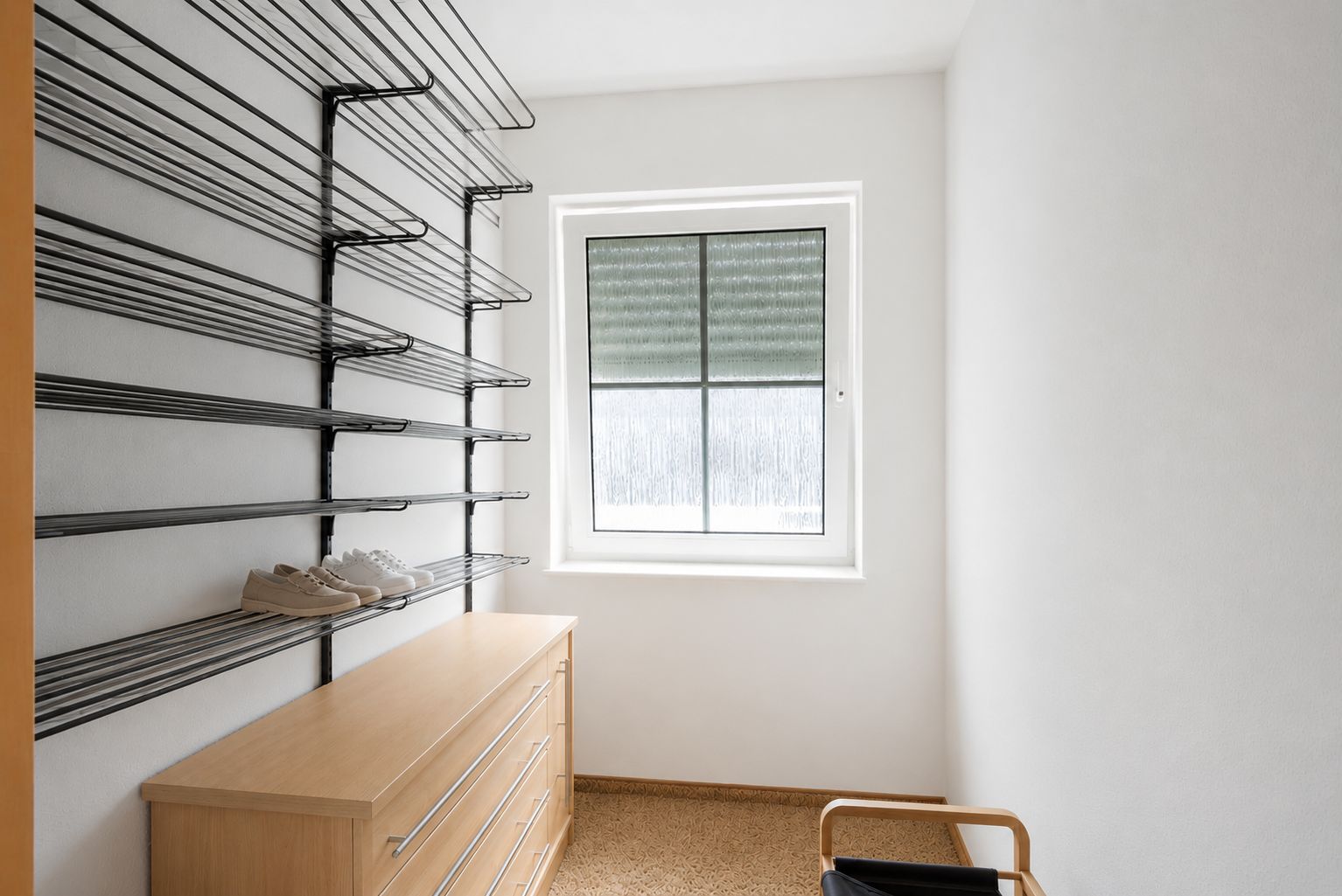 Heller Raum mit Wandregalen, Kommode und Fenster.