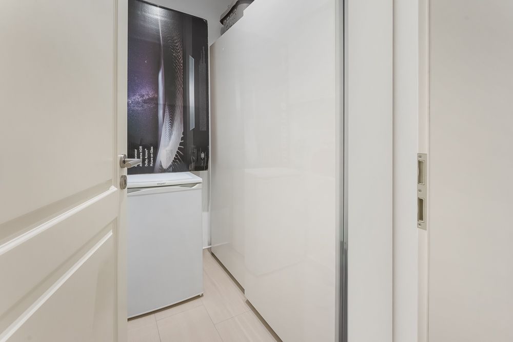 Kleiner Raum mit weißem Kühlschrank und weißem Schrank, Tür ist geöffnet.