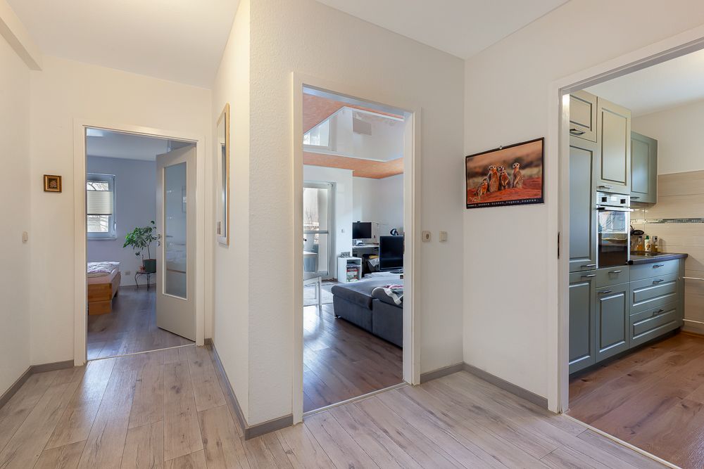 Flur einer Wohnung mit Blick in Schlafzimmer, Wohnzimmer und Küche mit Holzboden.