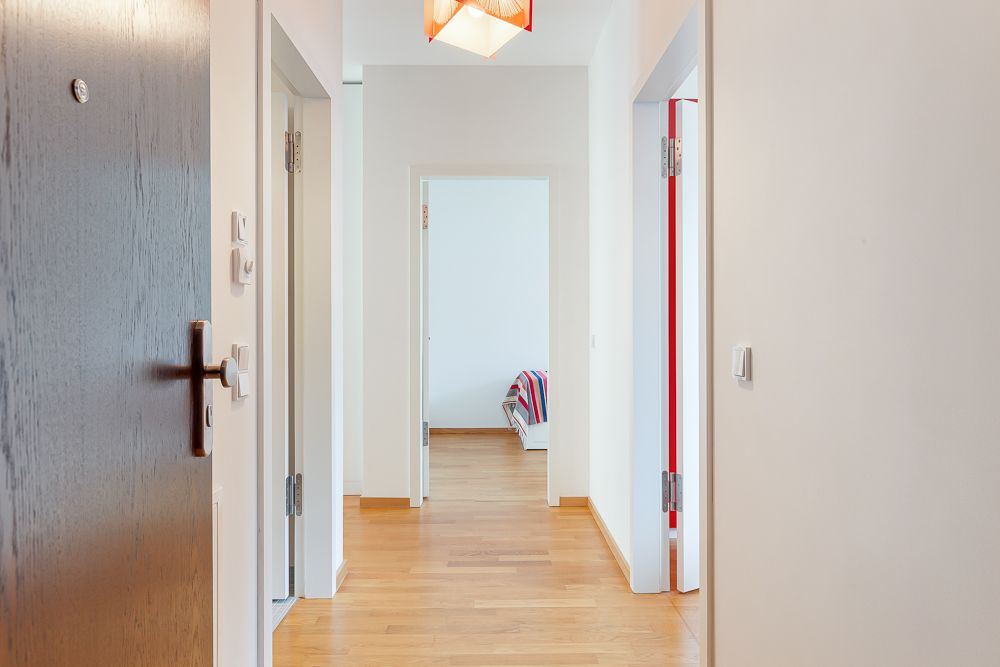Heller Flur mit Holzboden und mehreren offenen Türen in einer Wohnung.