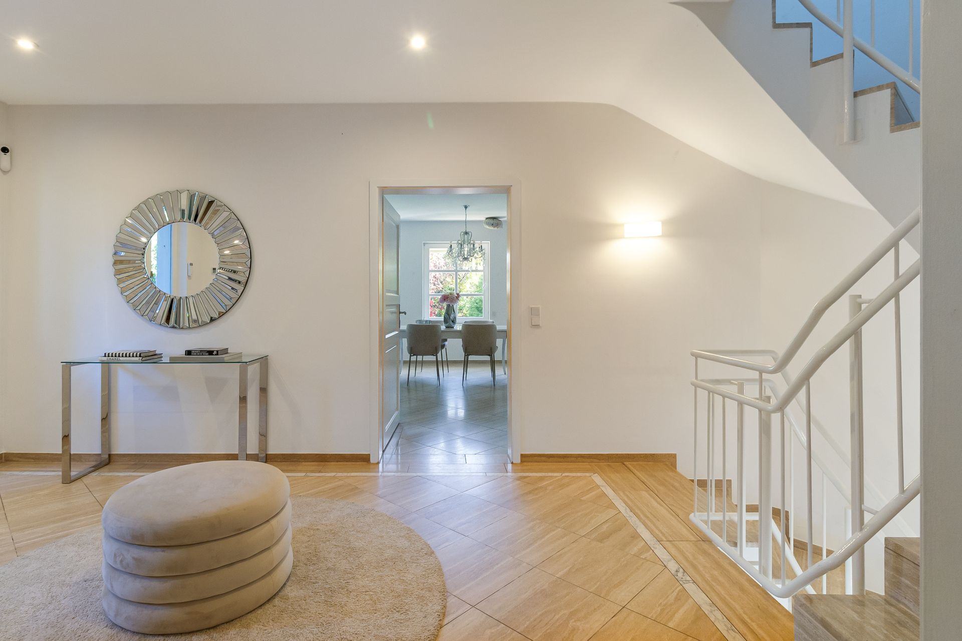 Heller Flur mit rundem Hocker, Spiegel, Konsole und Treppe, Blick ins Esszimmer.