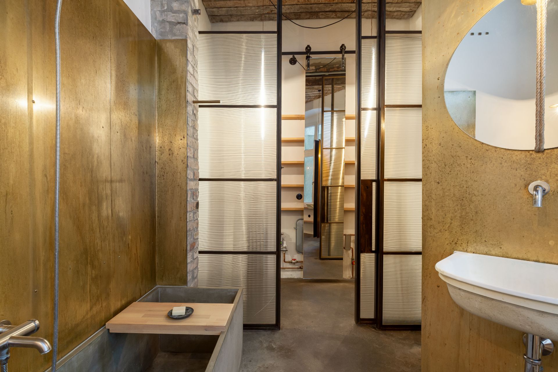 Modernes Badezimmer mit goldenen Wänden, Waschbecken, Dusche und Holzdetails.