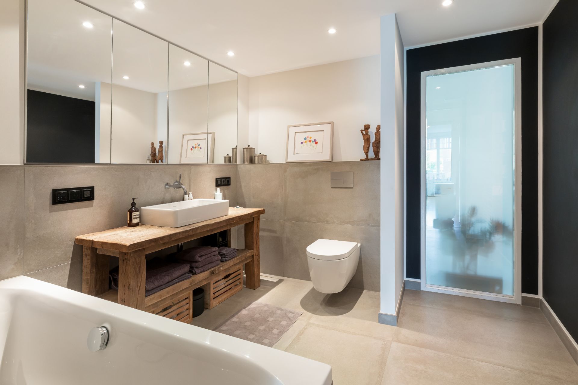 Modernes Badezimmer mit Holzwaschtisch, Spiegel, Toilette, Badewanne und Glasdusche.