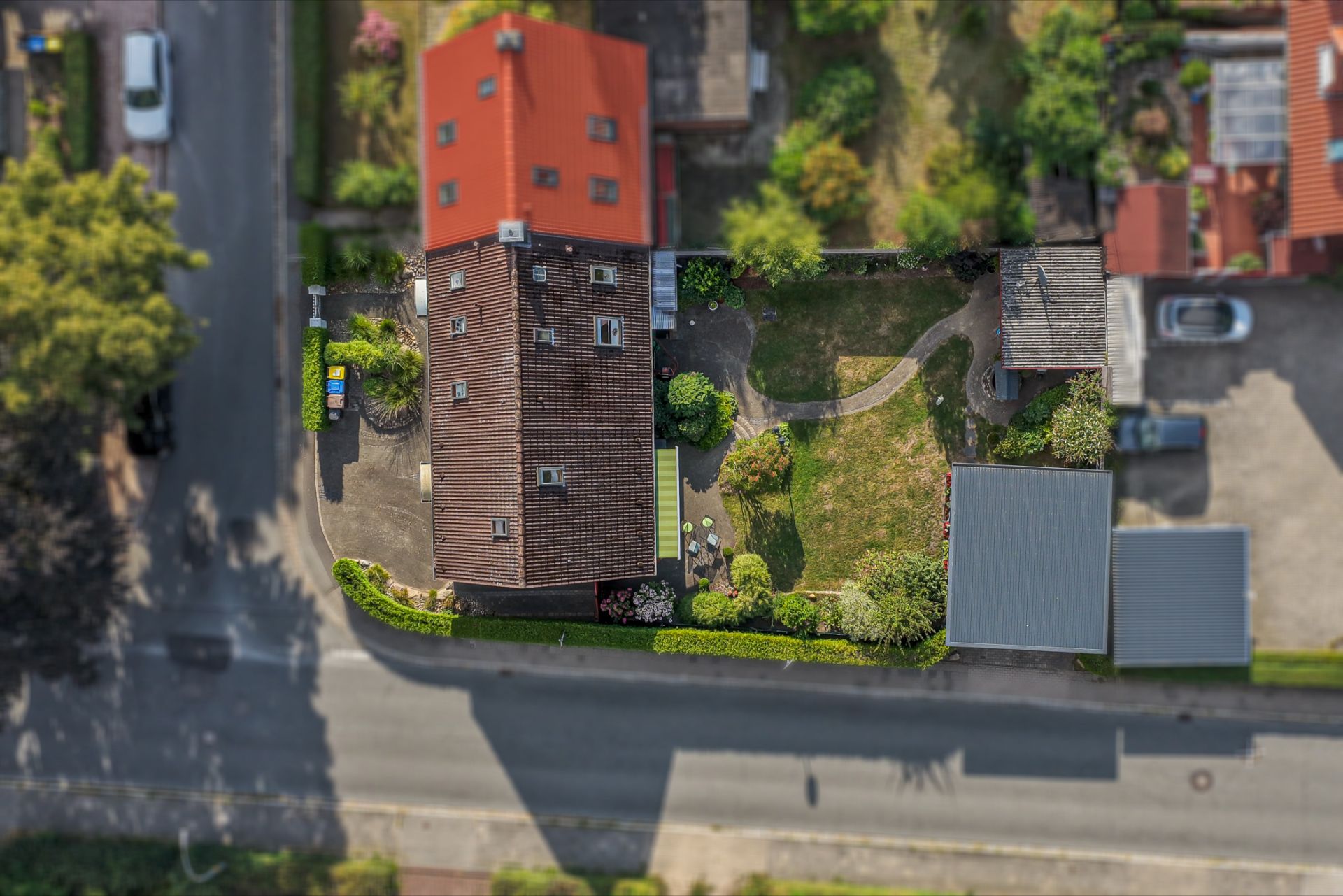 Luftaufnahme eines Wohnhauses mit Garten, Terrasse und angrenzender Straße.