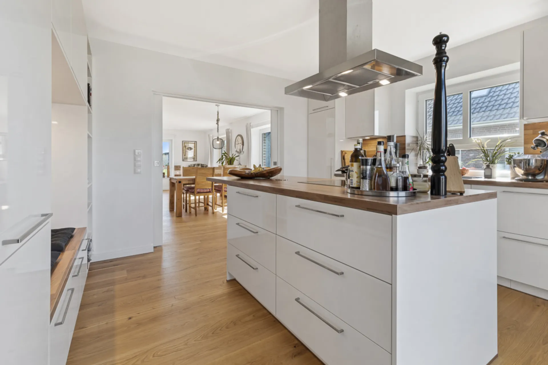 Moderne Küche mit Kochinsel, Holzboden und Blick ins Esszimmer.