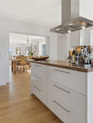 Moderne Küche mit Kochinsel, Holzboden und Blick ins Esszimmer.