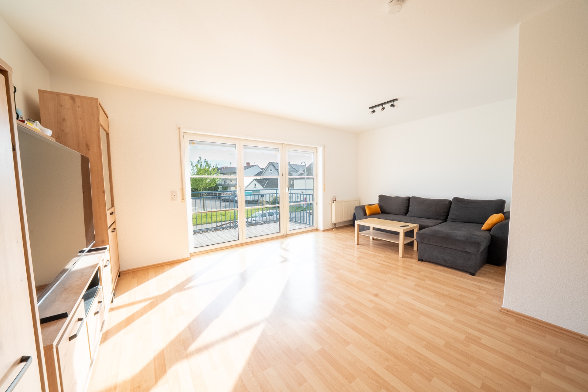 Helles Wohnzimmer mit grauem Sofa, Couchtisch und großem Fenster zur Terrasse.
