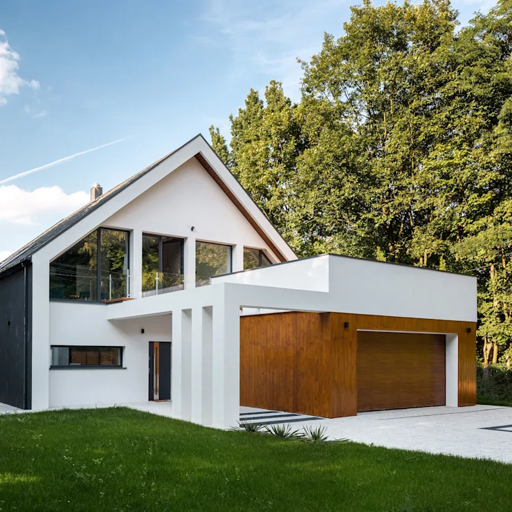 Modernes Einfamilienhaus mit großem Fenster, Holzgarage und Garten, Bäume im Hintergrund.