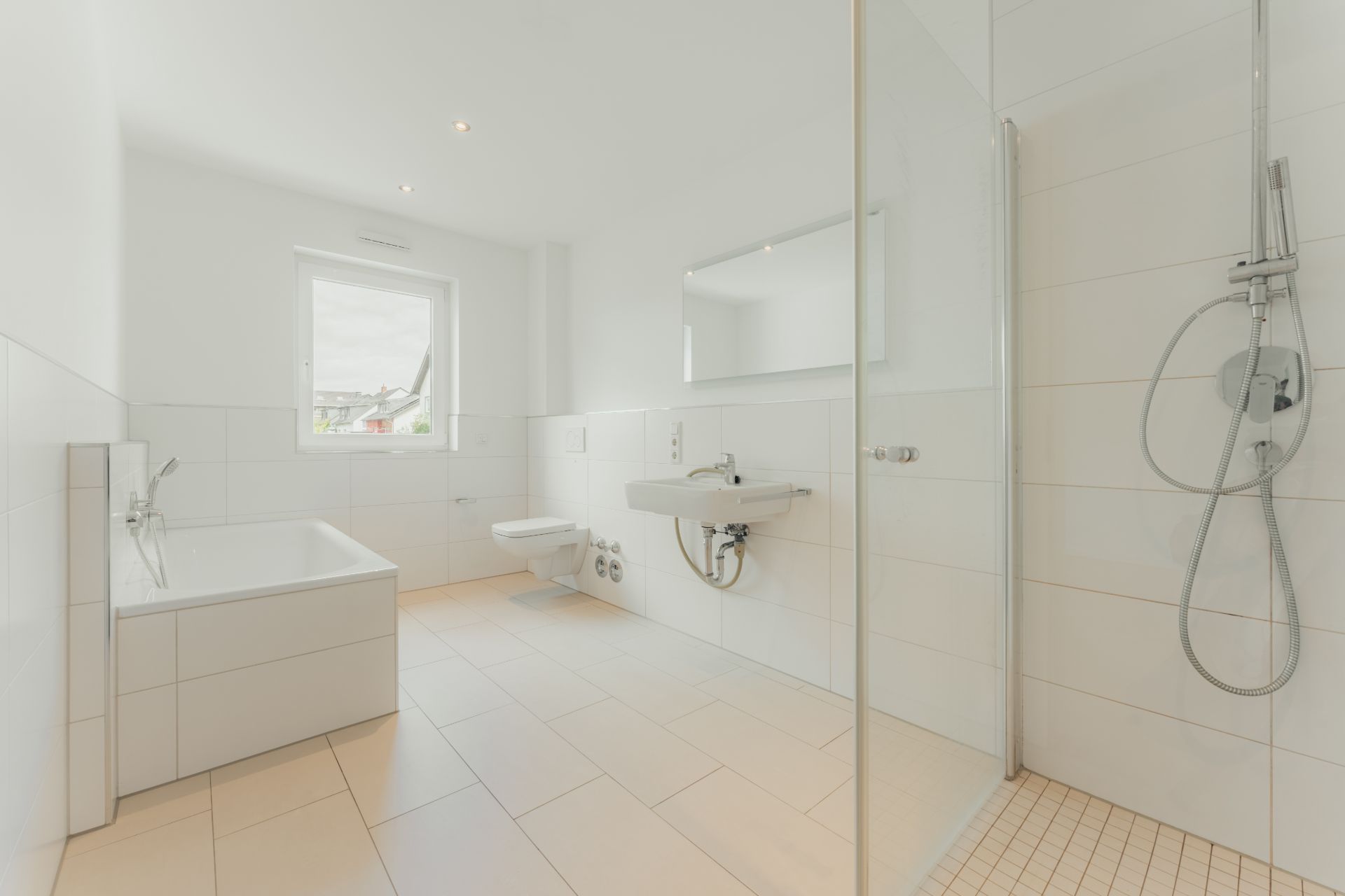 Helles Badezimmer mit Badewanne, Dusche, Waschbecken und Fenster.