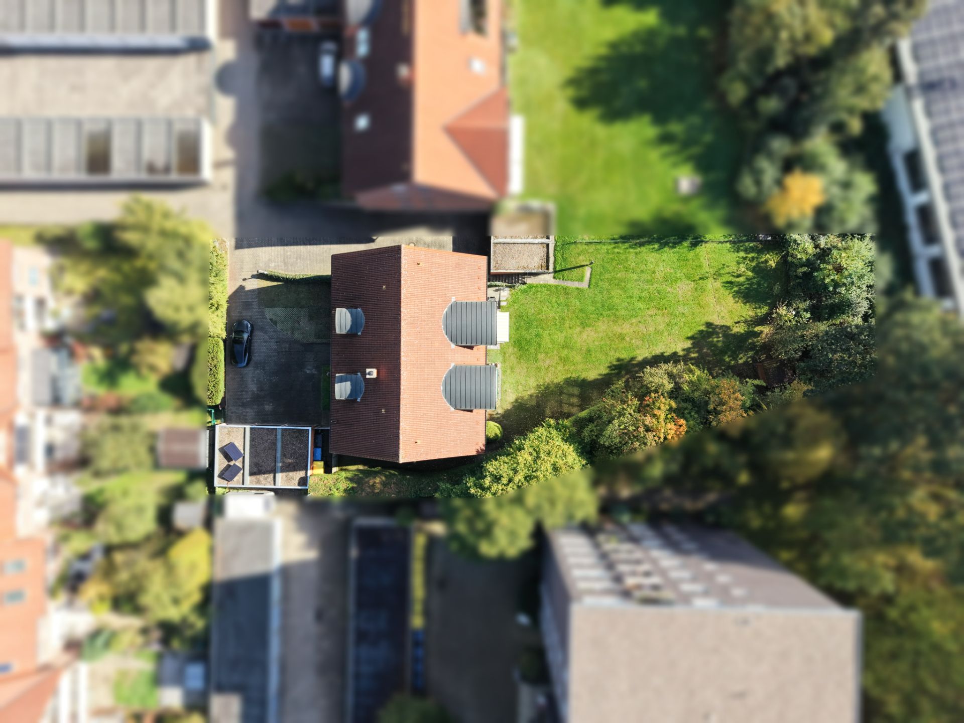 Luftaufnahme eines Einfamilienhauses mit Garten und angrenzender Terrasse.